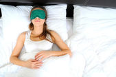 Mladá krásná žena spí v posteli s oční maskou