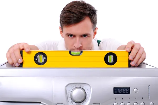 Человек держит уровень воздуха на верхней части стиральной машины — стоковое фото
