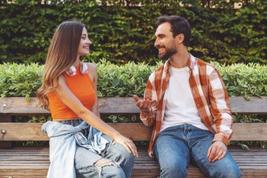 Genç mutlu çift parkta yürürken bankta otururken eğleniyor..