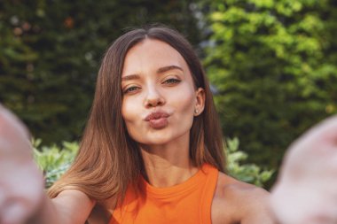 Bir yaz parkında bankta oturmuş video konferansı sırasında sohbet eden güzel bir kız..