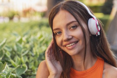 Genç ve güzel bir kız bankta oturmuş kulaklıkla müzik dinliyor..