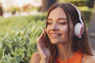 Genç ve güzel bir kız bankta oturmuş kulaklıkla müzik dinliyor..