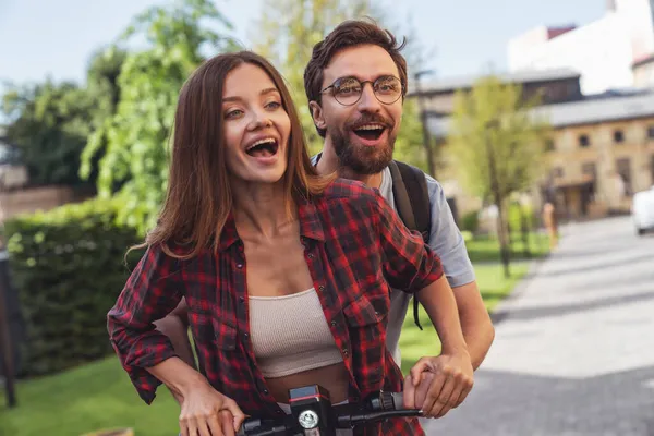 街の路上で電動スクーターに乗っている間 陽気な若いカップル — ストック写真