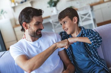 Mutlu küçük bir çocuk ve neşeli babası TV 'nin karşısında birlikte oturuyorlar ve evlerindeki en sevdikleri futbol takımı için neşeyle tezahürat yapıyorlar..