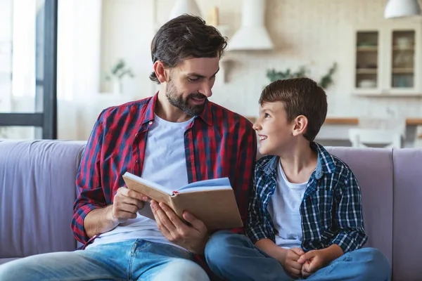Happy Little Boy His Cheerful Dad Reading Book Sitting Couch — Stock Photo, Image