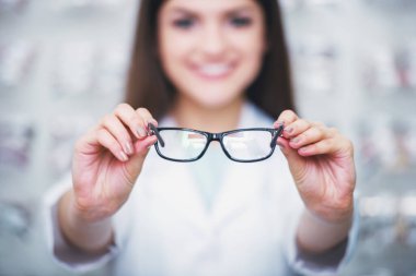 Optometrist gözlük dükkanındaki kameraya bakıyor. Profesyonel genç işçi kadın.