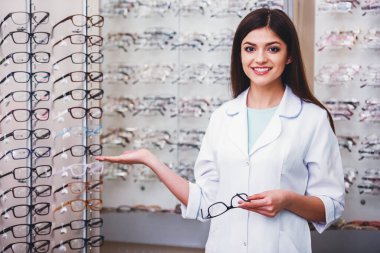 Optometrist gözlük dükkanındaki kameraya bakıyor. Profesyonel genç işçi kadın.