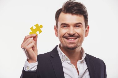 Yakışıklı işadamı beyaz arka plan üzerinde küçük yapboz gösteren.