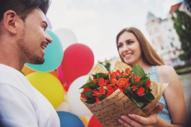 Romantik Tarih açık havada. Yakışıklı adam kadını çiçekler ve renkli balonlar ile şaşırttı. Çiçekler üzerinde odaklanmak.