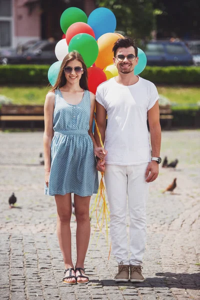年轻夫妇与五颜六色的气球对户外摄像机构成的全长 — 图库照片