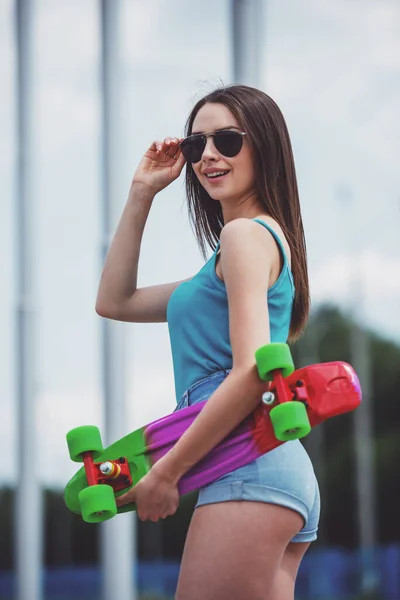 スケート ボードとサングラスで笑顔の美しい少女 — ストック写真