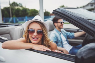 Güzel çift güneş gözlüğü cabriolet sürüş. Neşeli kadın kameraya arıyor.