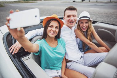 Cabriolet arka koltuklar üzerinde otururken selfie alarak üç güzel arkadaş.