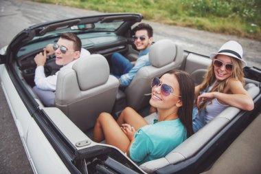 Mutlu arkadaş cabriolet üzerinde oturan ve uzağa bakarak güneş gözlüğü.