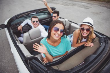 Cabriolet oturan, geriye dönüp baktığımda ve kameraya gülümseyen mutlu arkadaşlar.
