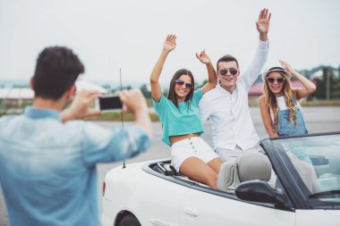 Mutlu arkadaş Cabriolet oturuyor. Genç adam alarak fotoğraf vasıl onun telefon.