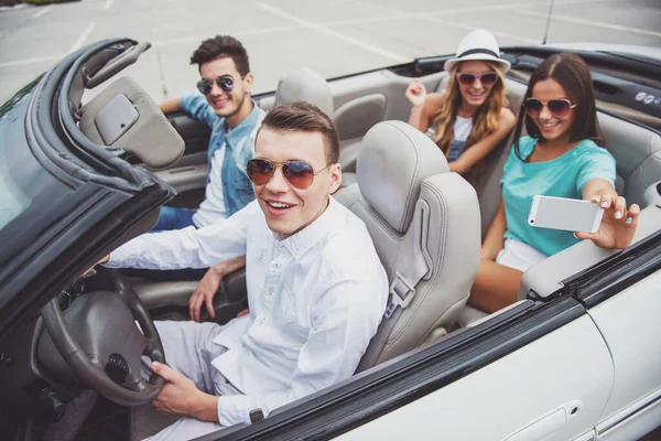 Mutlu arkadaş cabriolet oturma grubu. Arka koltuklarda bir selfie alarak güzel kızlar.
