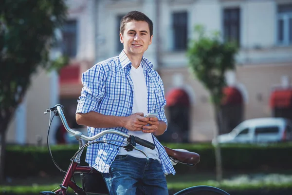 都市の彼の自転車の側に立って カメラ目線と笑顔の陽気な男 — ストック写真