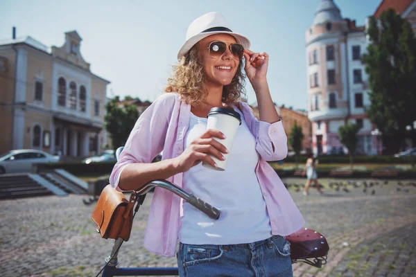 Mujer Joven Gafas Sol Con Bicicleta Sosteniendo Taza Café Mirando — Foto de Stock