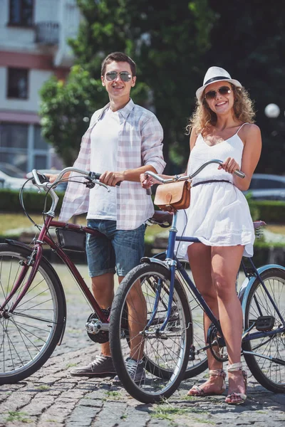 カメラ目線と自転車の近くに立っている間笑顔美しいカップル — ストック写真