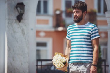 Buket çiçek ile yakışıklı genç kız arkadaşı için bekliyor.