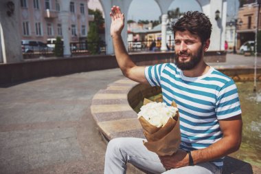 Buket çiçek ile yakışıklı genç kız arkadaşı için bekliyor.