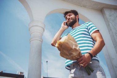 Buket çiçek ile yakışıklı genç kız arkadaşı için bekliyor.