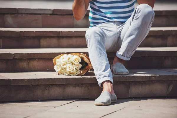 Genç adam akıllı rahat kıyafet buket çiçek ile kız arkadaşı bekliyor.