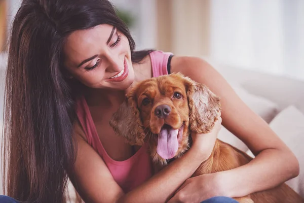 犬と幸せな若い女性がソファーに座っています — ストック写真