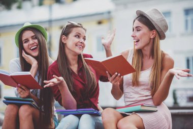 Üç güzel genç kız öğrencilerin yaz aylarında bir bankta oturan