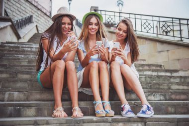 Üç güzel genç kadın şehirde, telefonunuzun ve açık havada yürümek