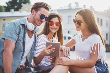 Arkadaşlık, eğlence ve insanlar kavramı. Birlikte iyi vakit geçiriyor, dijital tablet kullanma, açık havada, kasabada oturan gençler.