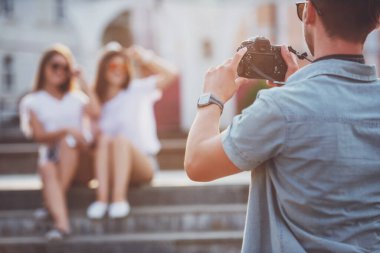 Arkadaşlık, eğlence ve insanlar kavramı. Arkadan görünüş gencin fotoğraf photocamera, açık havada, arkadaşlarıyla şehirde alıyor.