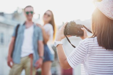 Arkadaşlık, eğlence ve insanlar kavramı. Arkadan görünüş genç kadının fotoğraf photocamera, açık havada, arkadaşlarıyla şehirde alıyor.