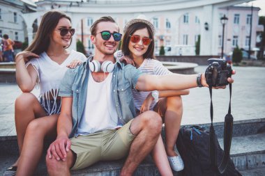 Arkadaşlık, eğlence ve insanlar kavramı. Gençler selfie fotoğraf fotoğraf fotoğraf makinesi ile açık havada, kasabada alıyor.