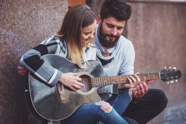 Genç, mutlu bir çift şehirde bir merdiven üzerinde duran gitar çalmak portresi