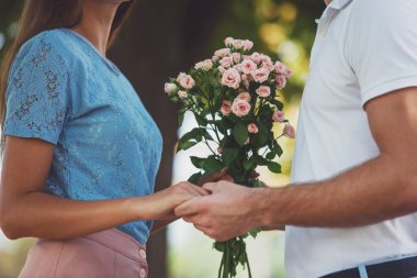 Parkta çiçeklerle buluşan sevimli genç çift.