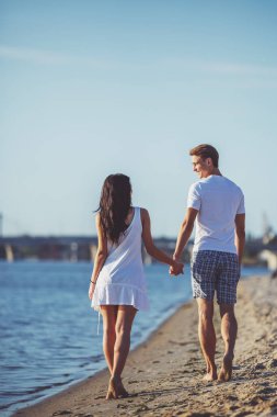 Yaz aylarında sahilde sevgi dolu genç bir çift yürüyüş