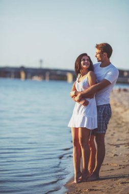 Yaz aylarında sahilde sevgi dolu genç bir çift yürüyüş