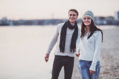 Sevgi dolu genç çift sahilde sonbaharda yürümek.