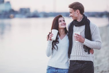 Sevgi dolu genç çift sahilde sonbaharda yürümek.