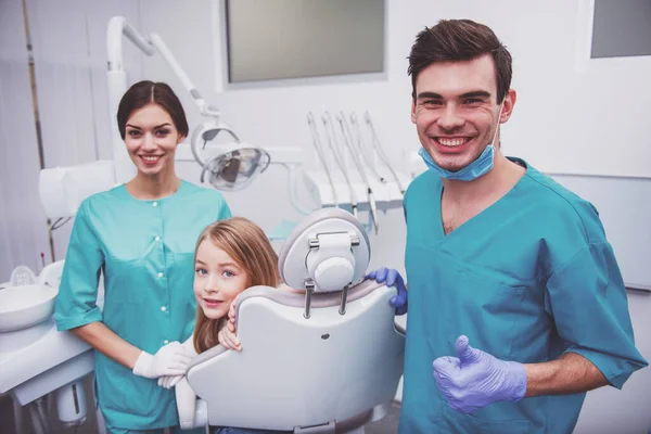 Niña Sentada Silla Dental Junto Asistente Dentista Mostrando Los Pulgares — Foto de Stock