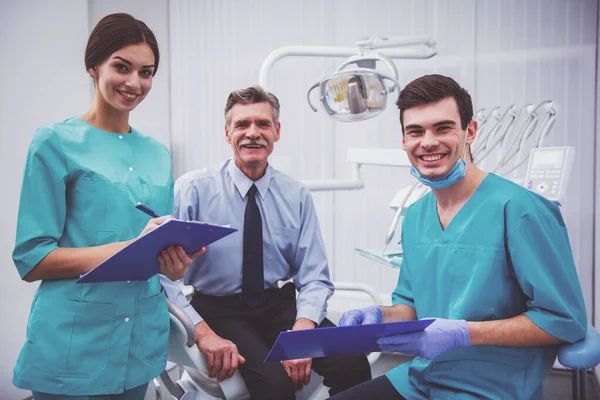 Jovem Médico Dentista Sua Assistente Gravação Nos Documentos Homem Idoso — Fotografia de Stock