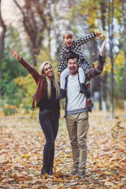 Sonbahar parkta yürürken genç mutlu aile.