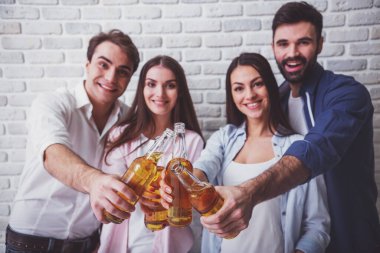 Şerefe! Mutlu gençlerin birbirlerine bağ ve tuğla duvar bir arka plan üzerinde duran bira ile şişe uzanan