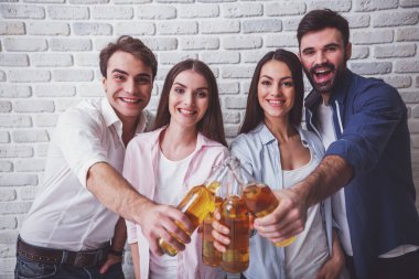 Şerefe! Mutlu gençlerin birbirlerine bağ ve tuğla duvar bir arka plan üzerinde duran bira ile şişe uzanan