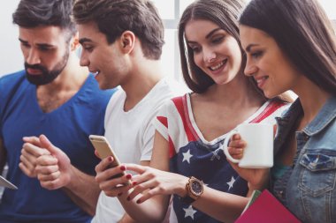 Tablet bilgisayar, Kupası, smartphone ve dizüstü bilgisayar, el altında tutmak dört genç çekici insanlar oturmak pencere kenarında, gülümseyen