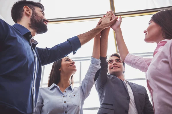 Grup genç iş adamları bir avuç kadar ayakta kollarını havaya kaldırdı ile vererek onların başarı ve onay belirtmek için