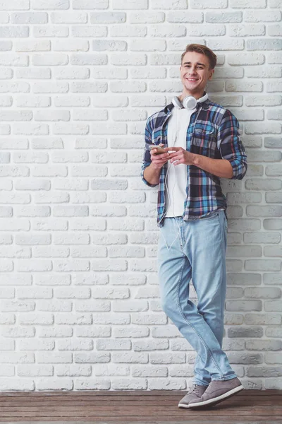 Jovem Homem Bonito Com Fones Ouvido Smartphone Posando Contra Pano — Fotografia de Stock