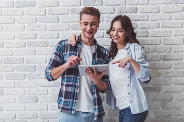 Happy Young Couple Using Tablet Dressed Fashionable Shirt Brick Wall — Stock Photo, Image